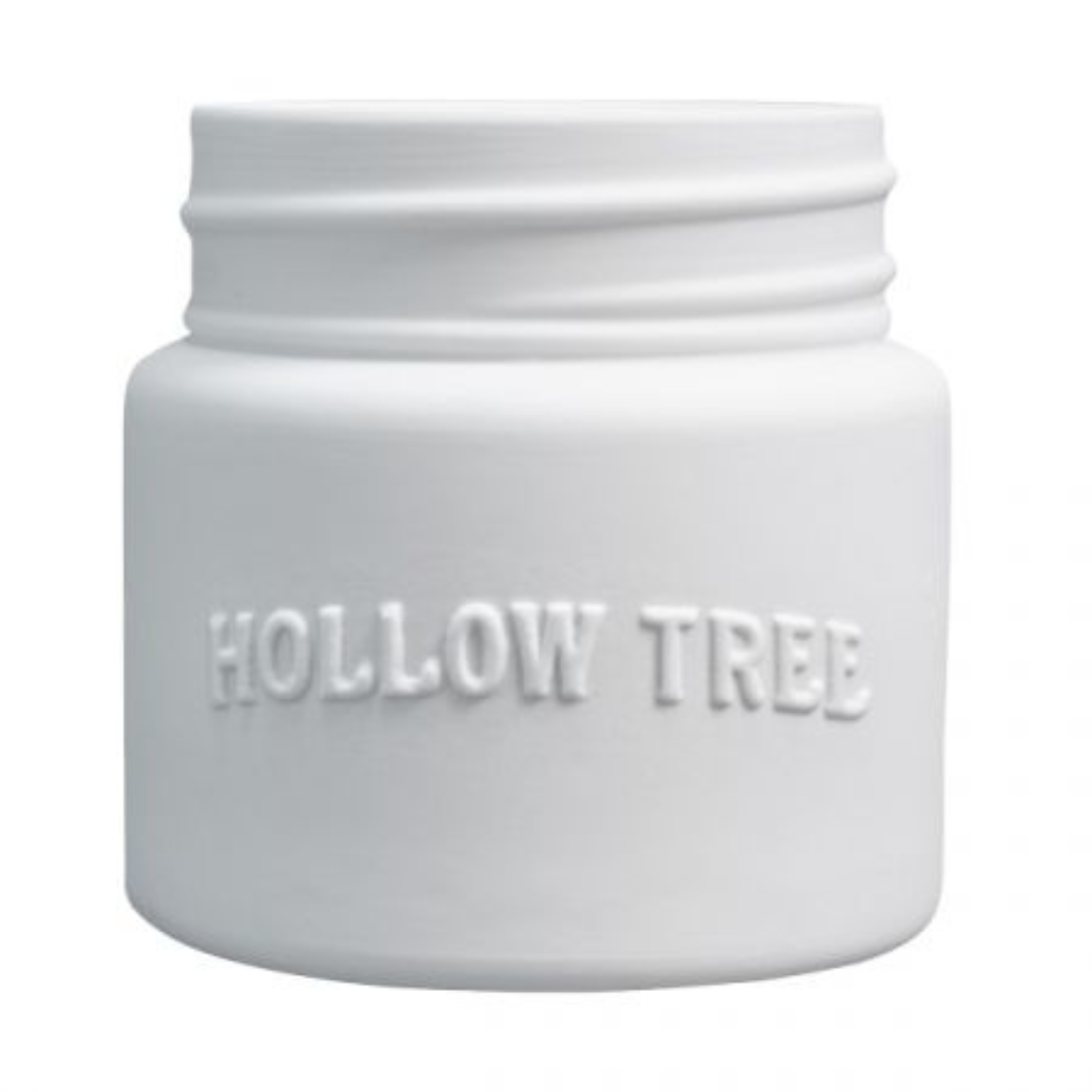 A white candle jar with 'HOLLOW TREE' embossed on the front