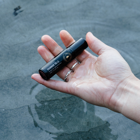 Hand holding a black cylindrical product with water in the background