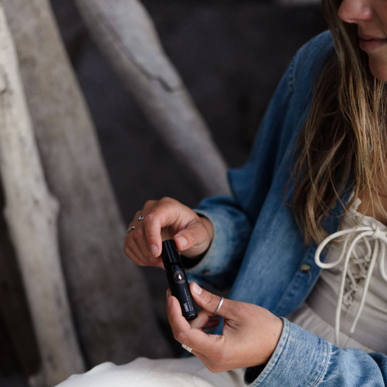 Perfume bottle with black cap held in hand, with labels visible