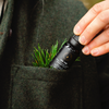 Hand holding black ribbed-cap diffuser oil bottle, label facing outward