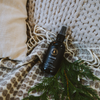 Room spray bottle with dark glass and black label reading Railroad, with pine sprigs nearby