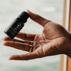 Raven diffuser oil bottle held in a hand, ribbed black cap and dark label