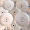 Set of ceramic candle catch dishes with pine logo on white dish