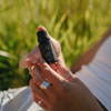 Hand holding Trails End diffuser oil bottle with black cap and dark label