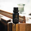 Diffuser oil bottle with black cap and label, standing on wood blocks